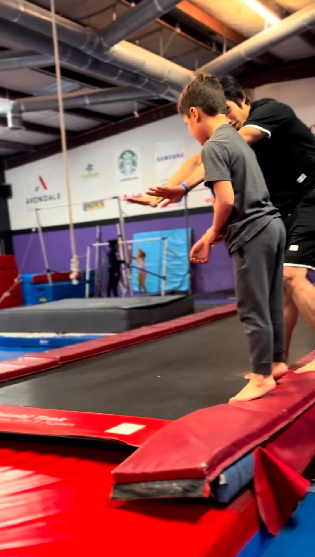 DFDub coach spotting young athlete at the gym